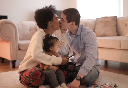 男人和女人抱着婴儿亲吻 · 免费素材图片
