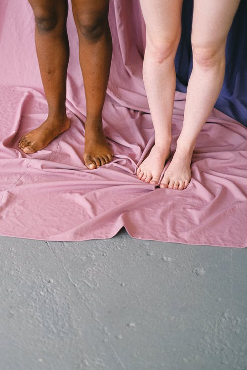人们赤脚踩着粉红色的纺织品 · 免费素材图片