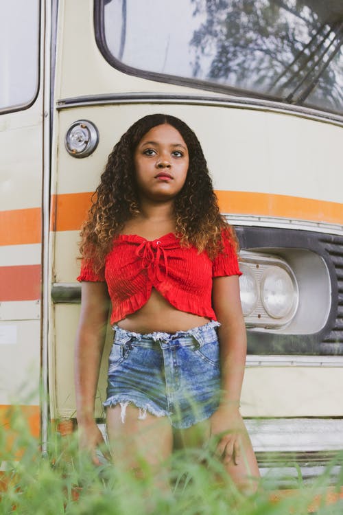 红色衬衫和蓝色牛仔短裤站在车旁的女人 · 免费素材图片