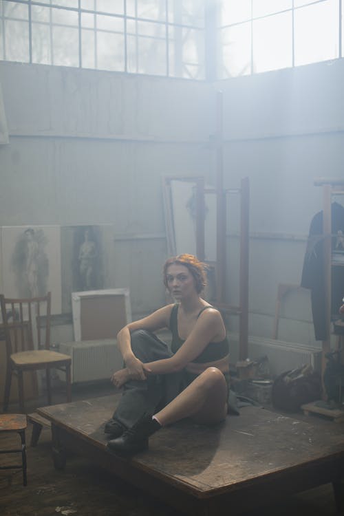 黑色背心坐在木制舞台上的女人 · 免费素材图片