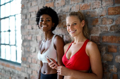 红色运动文胸的女人白色运动文胸的女人旁边 · 免费素材图片
