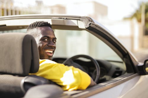 黄色衬衫驾驶一辆白色豪华轿车的人 · 免费素材图片