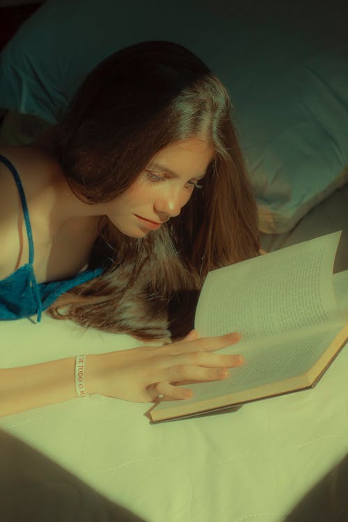 蓝色意大利面条表带顶部阅读书中的女人 · 免费素材图片
