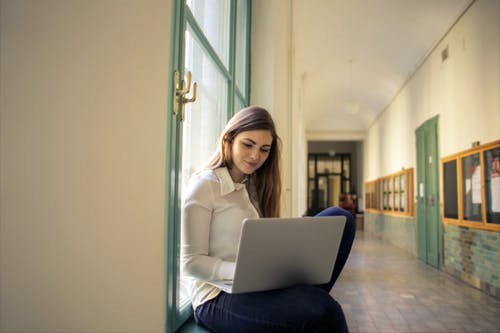 使用macbook的白色长袖衬衫的女人 · 免费素材图片