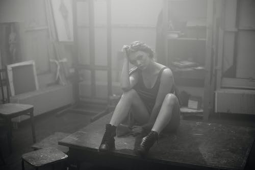 背心坐在木制舞台上的女人 · 免费素材图片