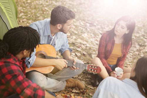 弹原声吉他，坐在草地上的人 · 免费素材图片