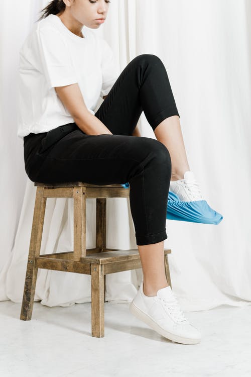白色的t恤和黑色的裤子，坐在棕色的木凳上的女人 · 免费素材图片
