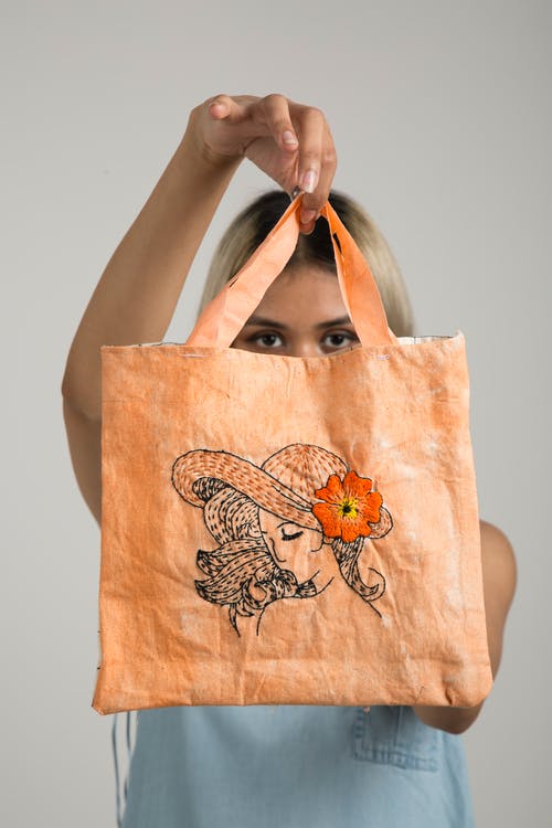 女人抱着橙色的袋子 · 免费素材图片