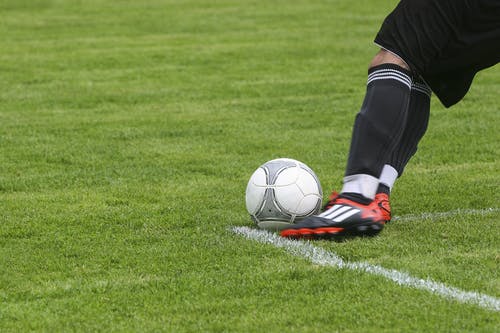 足球运动员在绿色草地上踢白灰色足球 · 免费素材图片