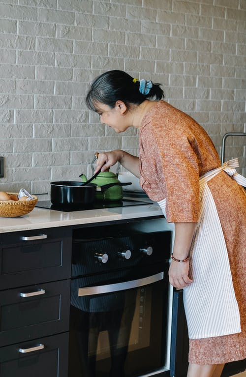 在现代的厨房里做饭的高级亚裔女子 · 免费素材图片