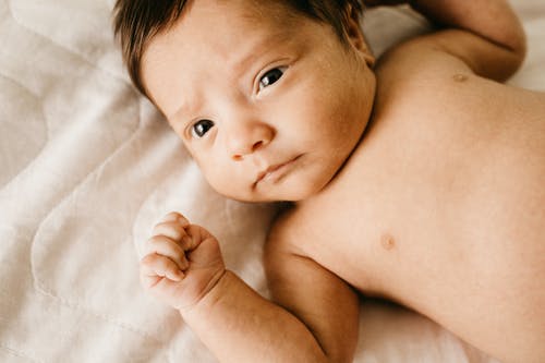裸照婴儿躺在床上的特写照片 · 免费素材图片