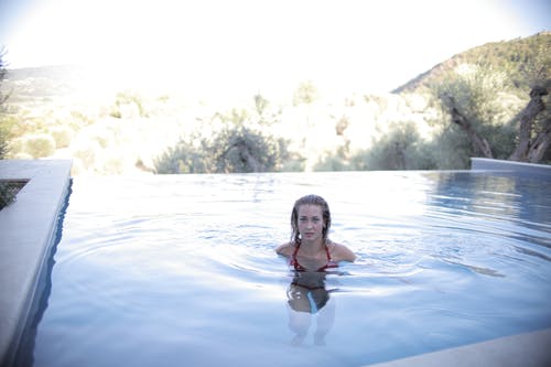 一个女人在游泳池里的红色比基尼的照片 · 免费素材图片