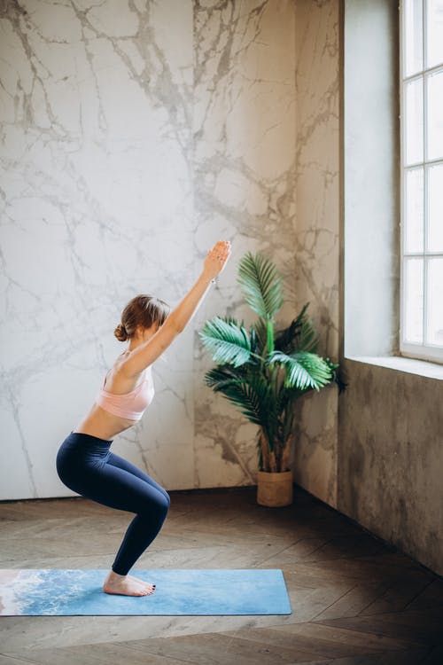 白色背心和黑色紧身裤，在瑜伽垫上做瑜伽的女人 · 免费素材图片