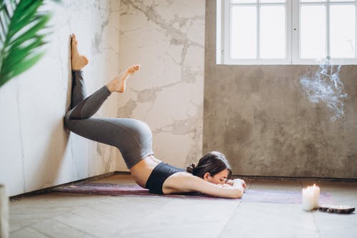 躺在瑜伽垫上做瑜伽的灰色紧身裤和黑色背心的女人 · 免费素材图片