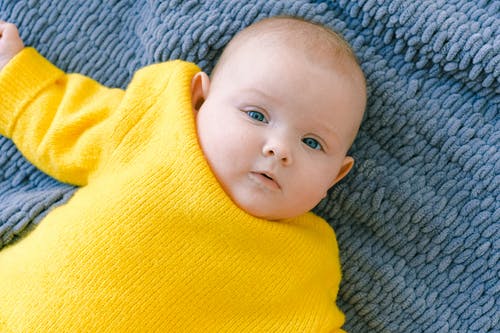 婴儿躺在灰色纺织的黄色衬衫 · 免费素材图片