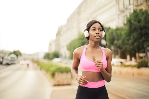 粉红色运动胸罩和黑色紧身裤慢跑的女人 · 免费素材图片