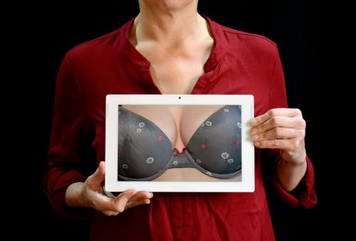 女人抱着白色平板电脑显示灰色胸罩 · 免费素材图片
