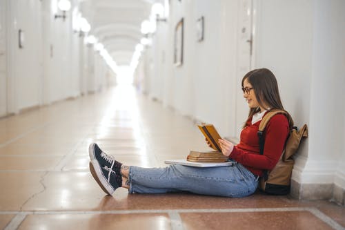 读一本书时坐在走廊上的女人的照片 · 免费素材图片