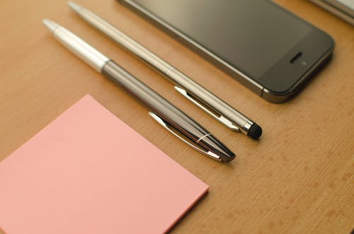 桌上的iphone旁边的两个单击笔 · 免费素材图片