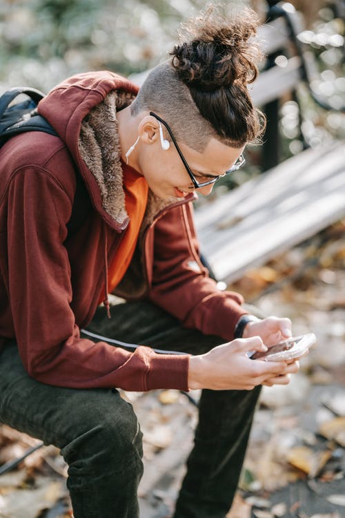 红色外套和灰色的裤子，拿着智能手机的人 · 免费素材图片