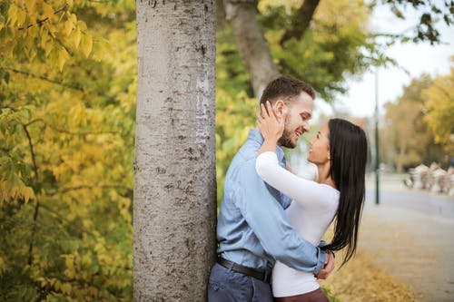 夫妇在树干旁边拥抱 · 免费素材图片