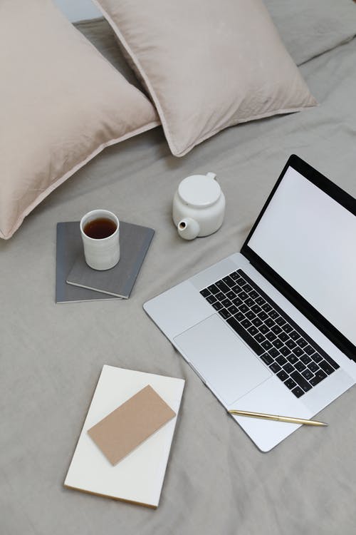 桌上的白色陶瓷杯旁边的macbook Pro · 免费素材图片