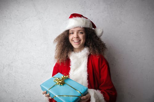 幼儿在红色的圣诞老人的帽子，拿着蓝色的圣诞节礼物 · 免费素材图片