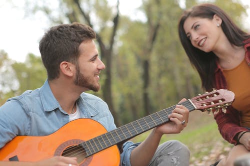 男人在女人旁边弹吉他的照片 · 免费素材图片