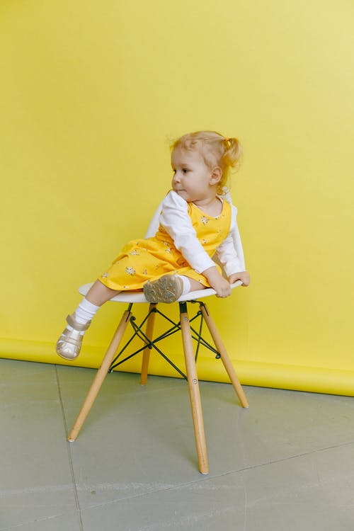 白色和黄色的长袖连衣裙，坐在木折叠椅上的女孩 · 免费素材图片