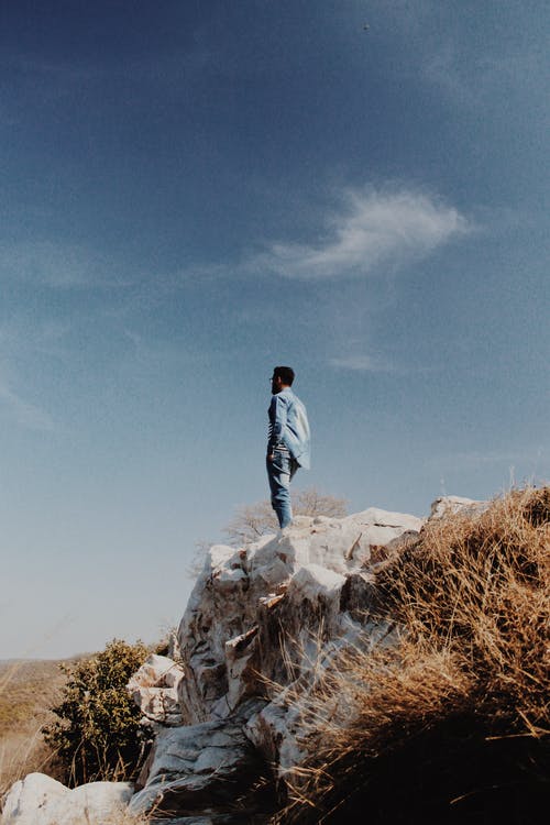 一个人站在岩层上的照片 · 免费素材图片