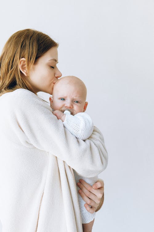 白色长袍抱婴儿的女人 · 免费素材图片
