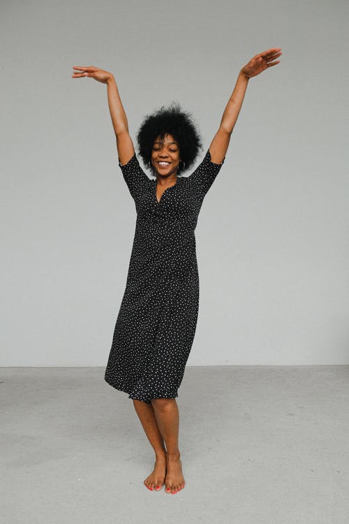黑色和白色的圆点裙举起双手的女人 · 免费素材图片