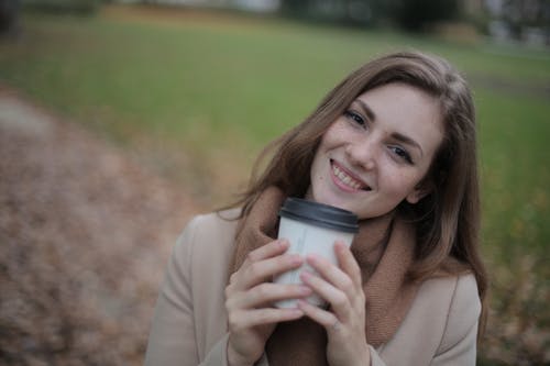 米色的长袖衬衫，拿着灰色杯的女人 · 免费素材图片