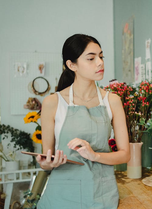 平板电脑在花卉商店集中的女人 · 免费素材图片