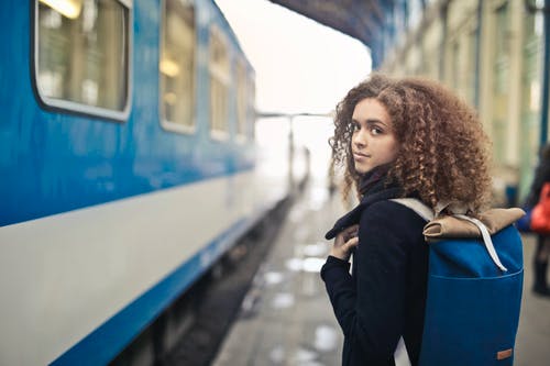 黑色外套站在蓝色和白色火车旁边的女人 · 免费素材图片