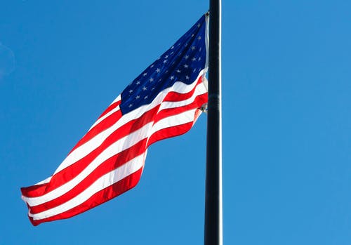 低角度观的国旗，映衬在蓝天下 · 免费素材图片