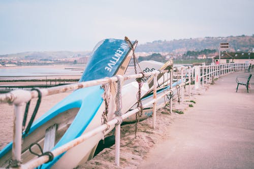 白色和蓝色小船在白色栏杆旁边的照片 · 免费素材图片