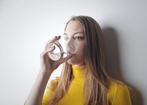 喝水时穿黄色针织毛衣的女人 · 免费素材图片