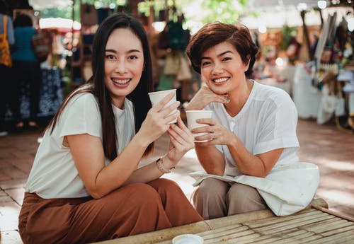 相当亚裔妇女用坐在室外咖啡馆的外卖咖啡 · 免费素材图片