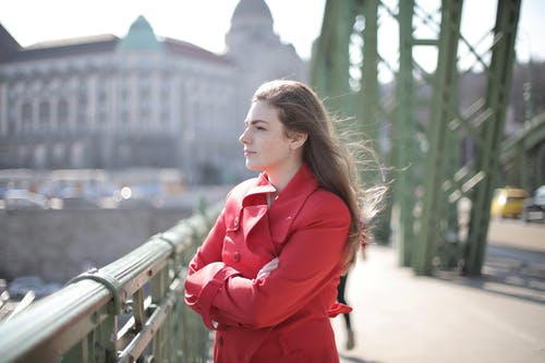 站在金属栏杆附近的红色外套的女人 · 免费素材图片