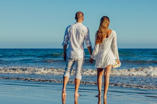 夫妇在晴朗的天空下海滩上的后视图 · 免费素材图片