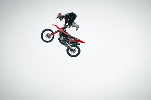 黑色和红色越野摩托车西装骑越野摩托车越野自行车的人 · 免费素材图片