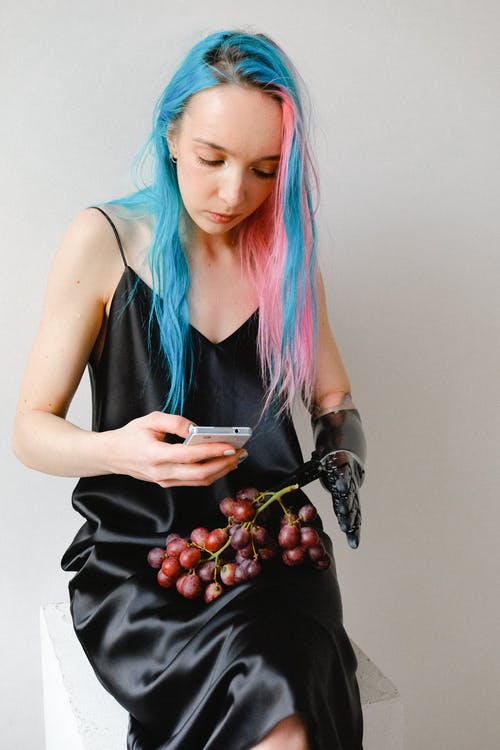 拿着智能手机和一串葡萄的黑色便裙的女人 · 免费素材图片