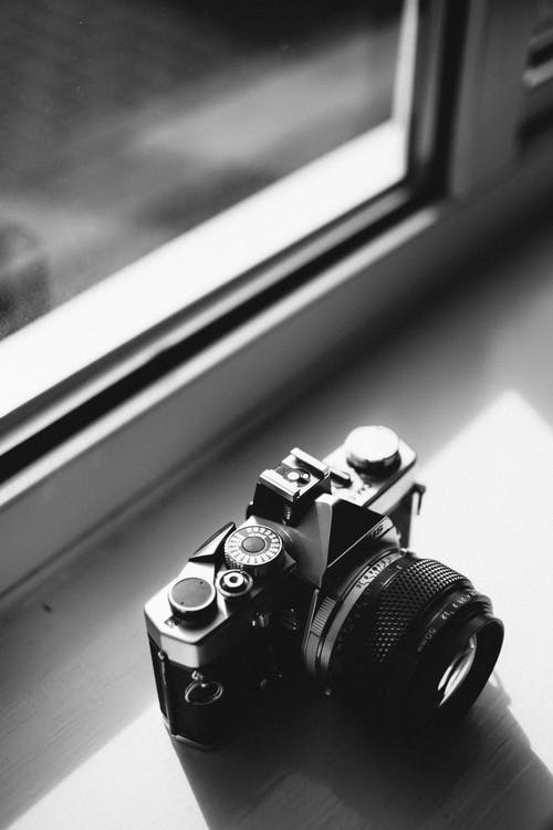 靠近窗户的古典相机的灰度照片 · 免费素材图片