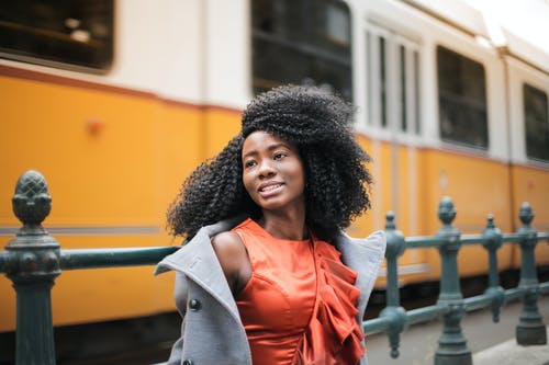 站在黄色的火车附近的灰色外套的女人 · 免费素材图片