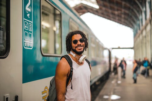 身穿黑色墨镜，站在火车旁边的白色背心的男人 · 免费素材图片