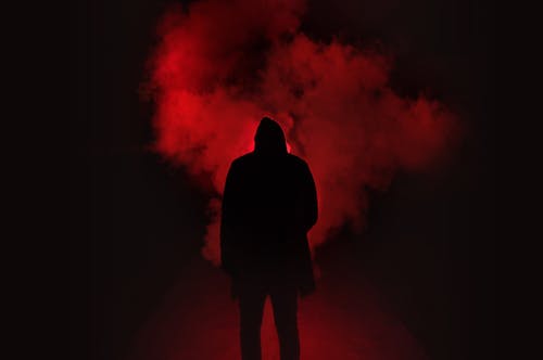 男子站在黑色和红色背景下的剪影 · 免费素材图片