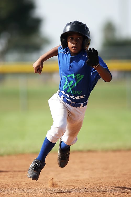 白天在棕色的土壤场上运行的蓝色和白色棒球球衣的男孩 · 免费素材图片