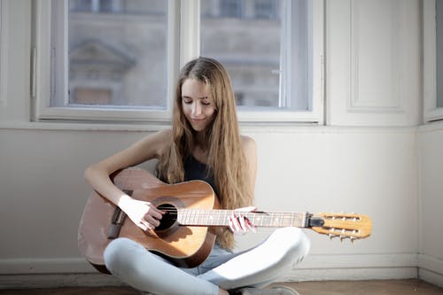 女人弹棕色原声吉他 · 免费素材图片