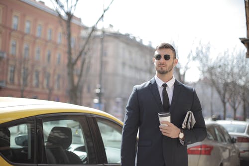 站在黄色汽车旁边的黑色西装的男人 · 免费素材图片